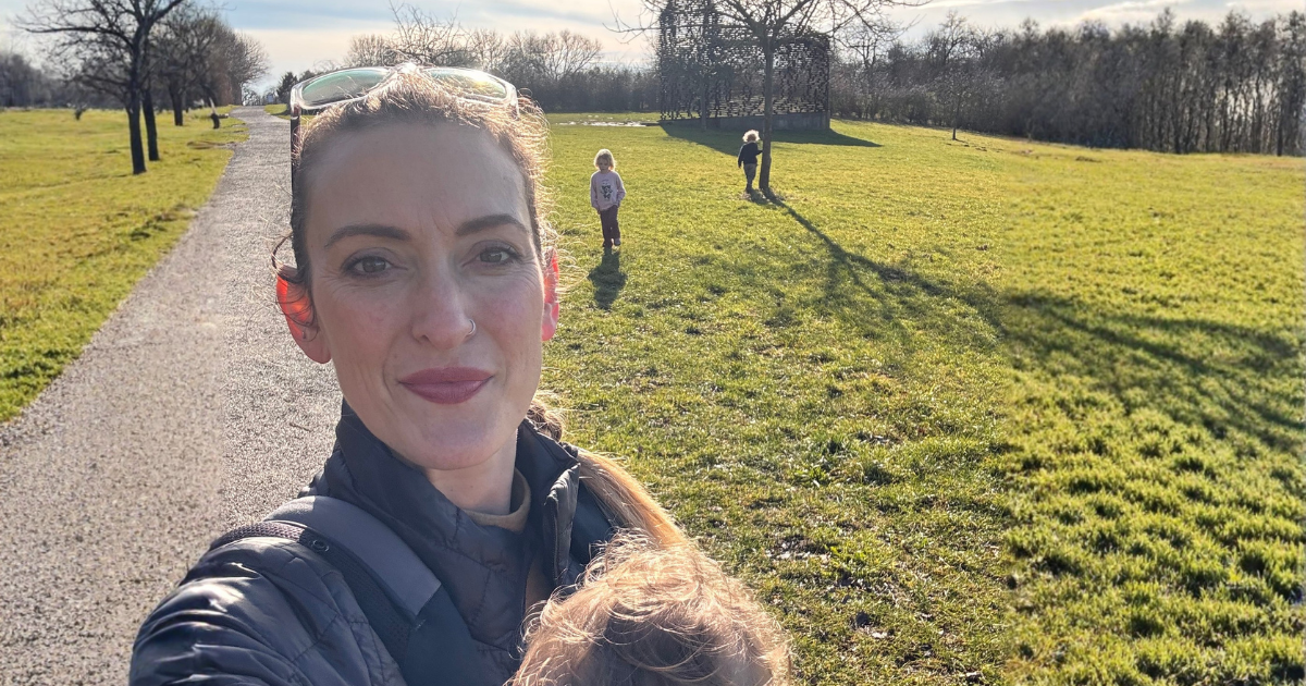 Karlien buiten in de zon met haar kinderen op de achtergrond, als symbool voor kiezen voor vrijheid en bewuster leven.