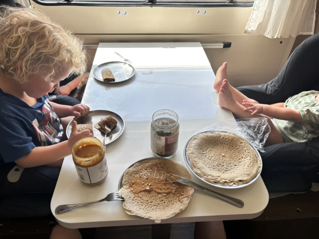 Kinderen eten pannenkoeken met pindakaas aan tafel in de camper